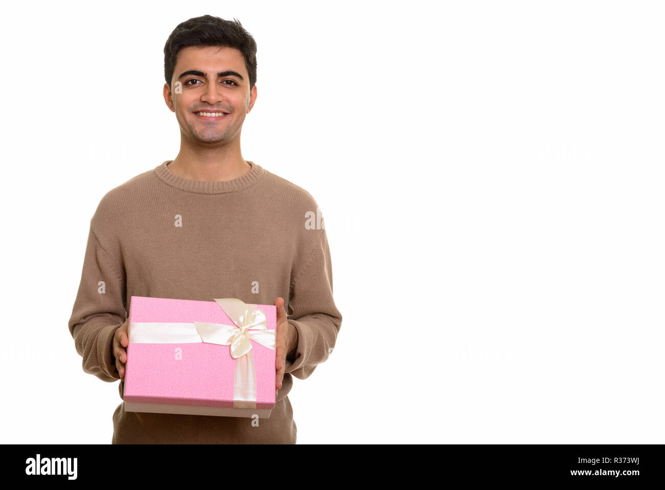 Young happy Persian man holding gift box ready for Valentine's d Stock Photo