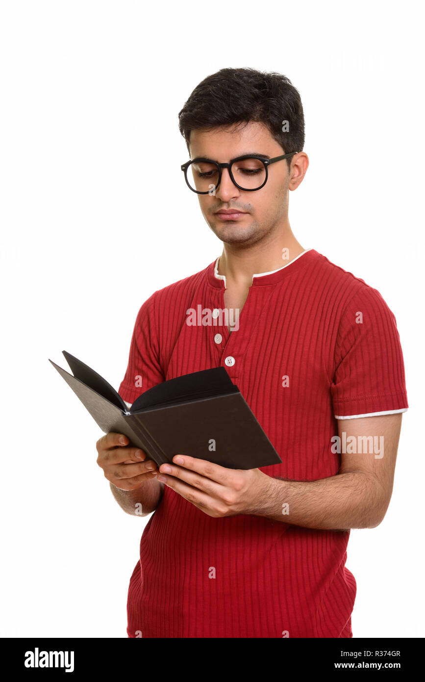 Portrait of young handsome Persian man reading book Stock Photo