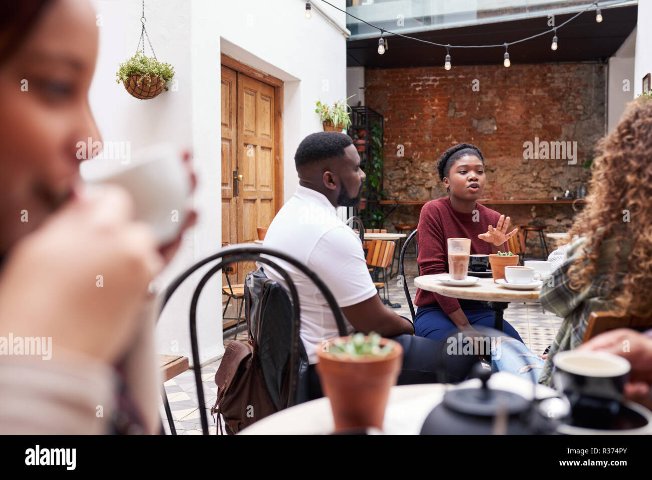People talking together over coffee in a trendy cafe courtyard Stock Photo