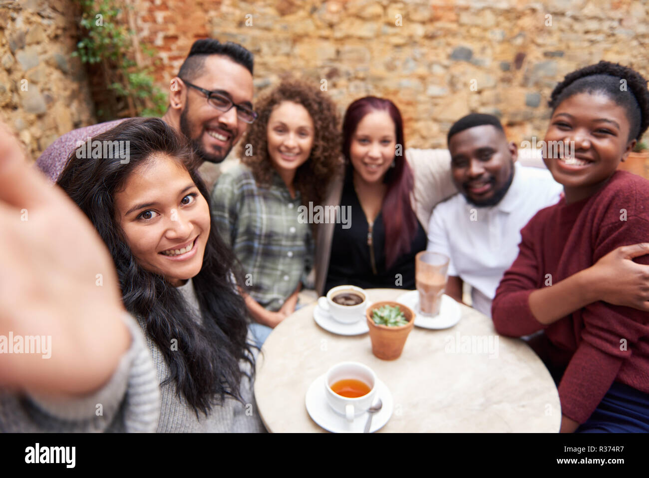 Diverse friends taking selfies in a trendy cafe courtyard Stock Photo