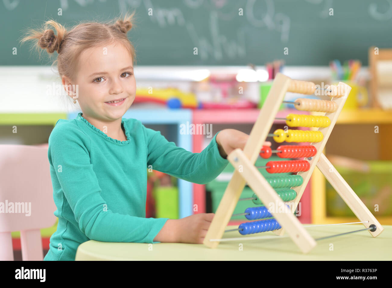 Portrait of little girl sitting and counting on abacus Stock Photo