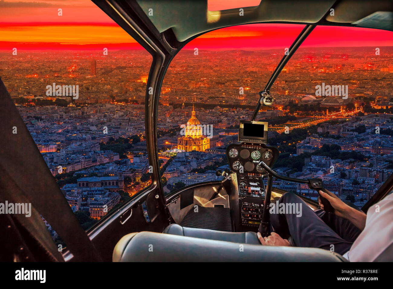 Helicopter cockpit flying aerial view of national residence of the Invalids palace at sunset in Paris, French capital, Europe. Scenic flight above Paris skyline on red sunset background. Stock Photo