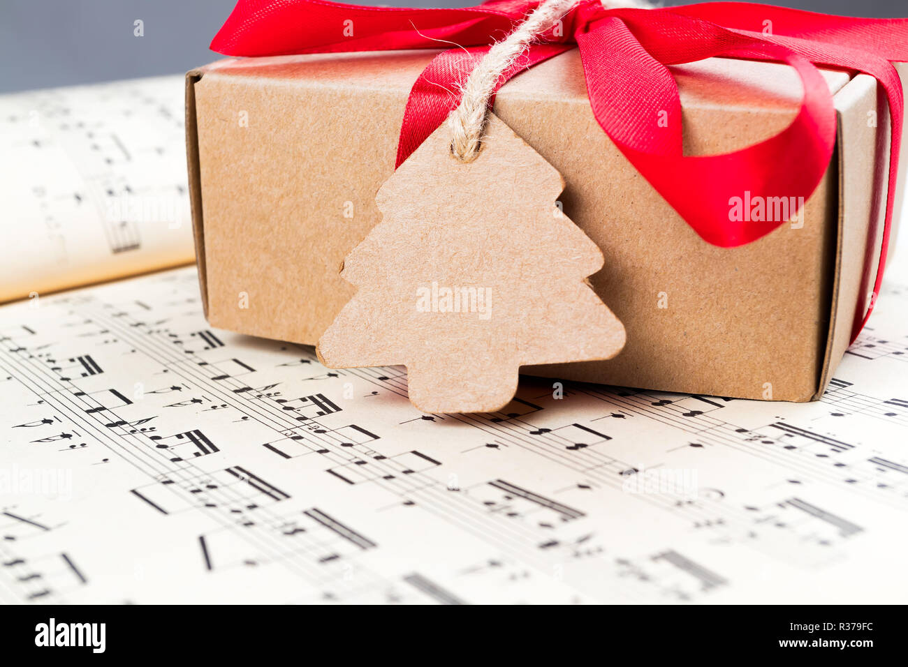 Christmas gift or present with label and twine on music sheet. Red ribbon bow. Notes Stock Photo