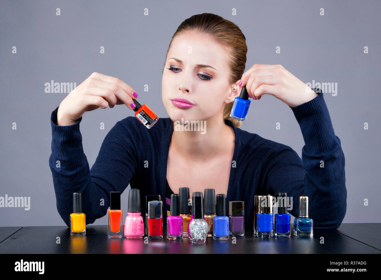 Dilemma of a young woman in front of nail polish Stock Photo