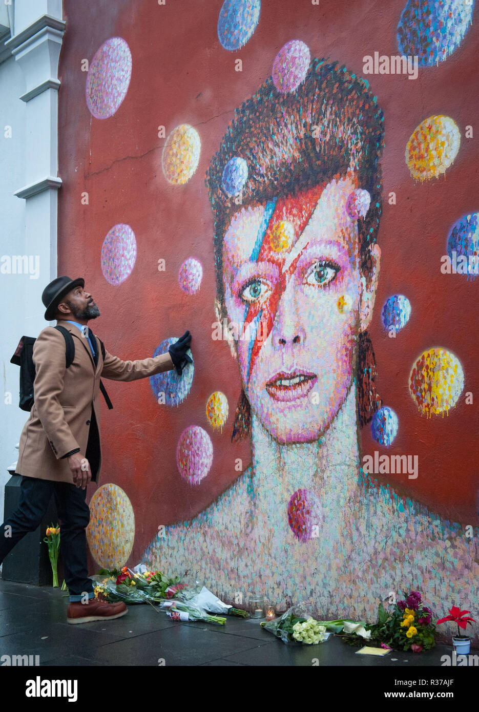 Tunstall Road, London, UK. 11th January, 2016. London, UK. Mourners lay flowers at  the foot of the David Bowie mural in Brixton.  Pictured: A fan loo Stock Photo