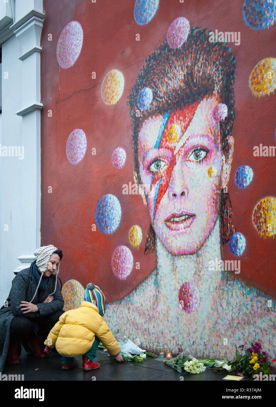 Tunstall Road, London, UK. 11th January, 2016. London, UK. Mourners lay flowers at  the foot of the David Bowie mural in Brixton.  Pictured: A young f Stock Photo