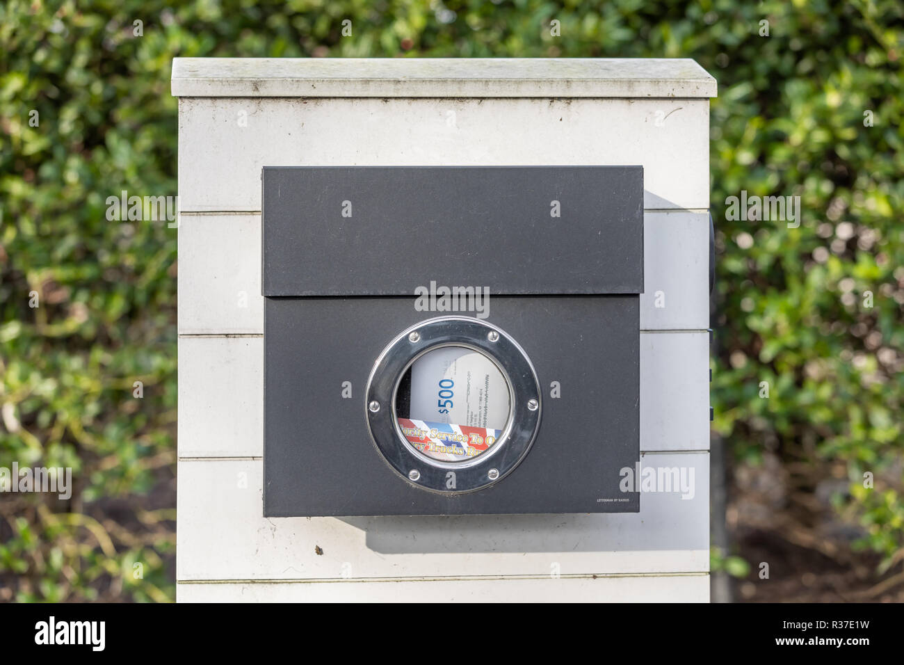 Junk mail in a mail box with a round window Stock Photo