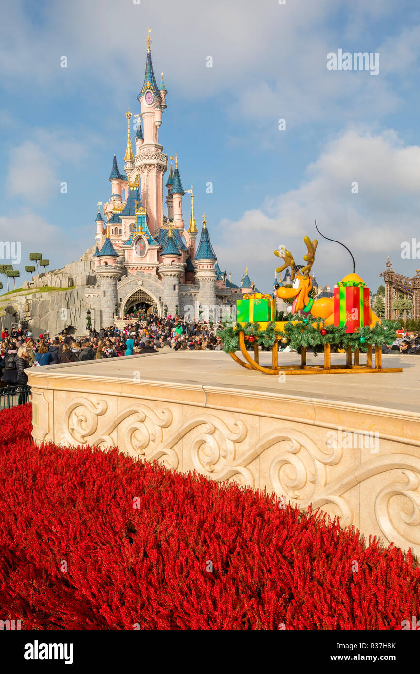 Disneyland Paris, France, November 2018: Sleeping Beauty's Castle with blue skies behind and red flowers in front Stock Photo