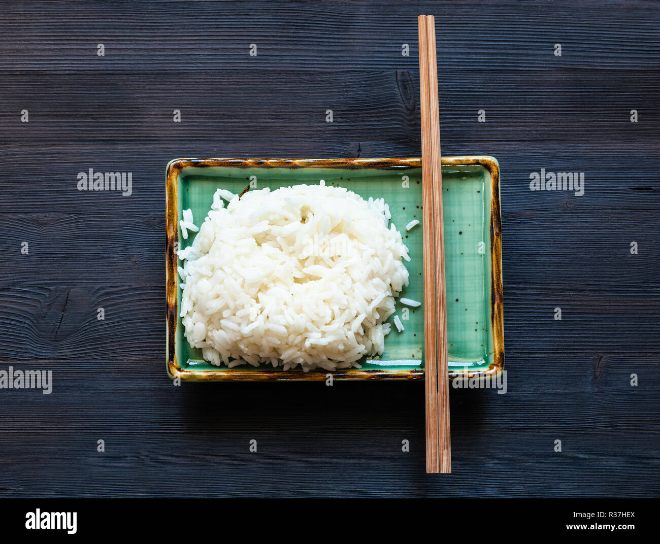 Top View Of Portion Of Boiled Rice And Chopsticks On Green Plate On Dark Wooden Board Stock Photo Alamy