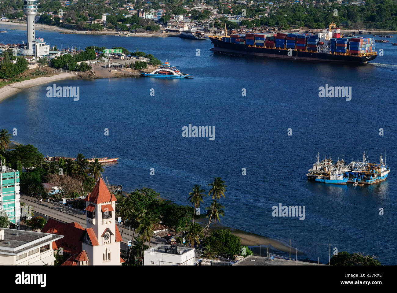 TANZANIA Daressalaam, bay and seaport, Pacific International Lines PIL container ship sailing to indian ocean, in front protestant Azania Front cathedral, built during german colonial time, Kigamboni Ferry Terminal Stock Photo