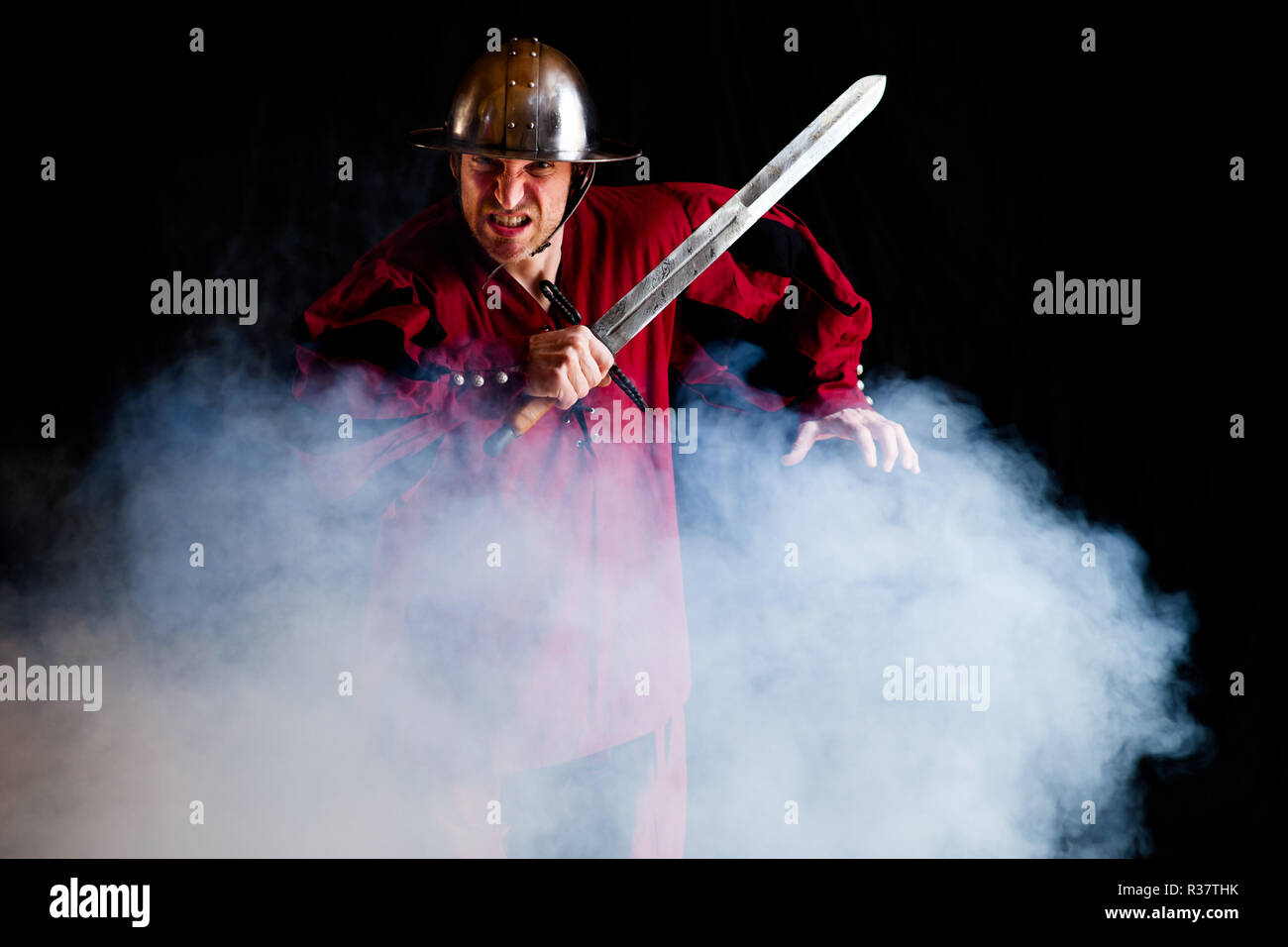Man, with helmet and sword in fog, fighting pose, Germany Stock Photo
