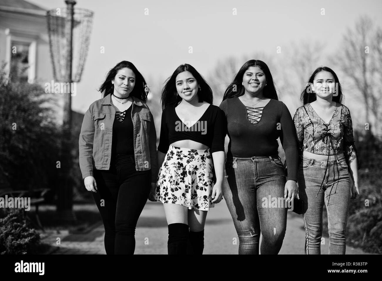 Group of four happy and pretty latino girls from Ecuador posed at street. Stock Photo