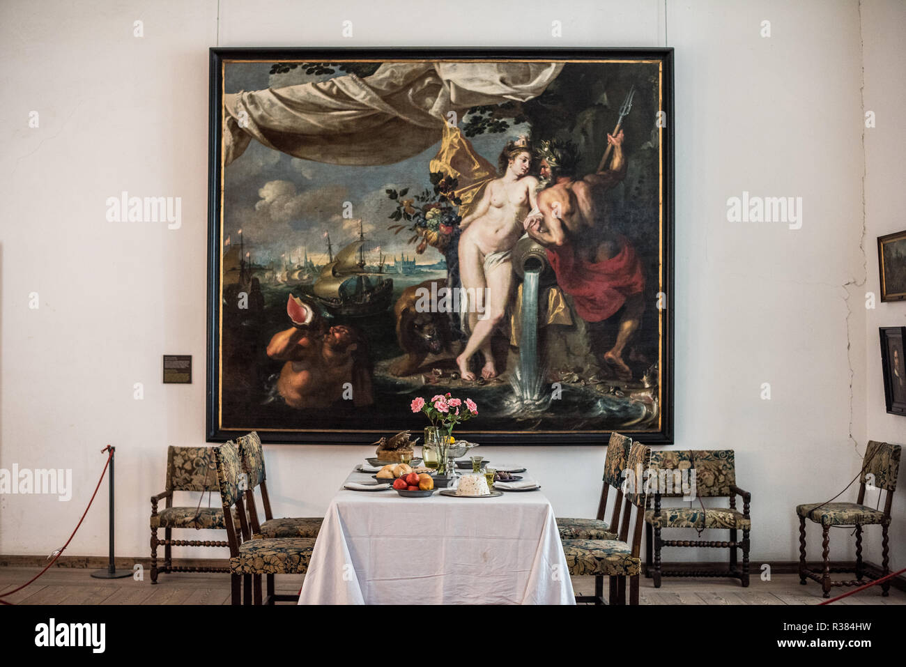 HELSINGØR, Denmark — A large oil on canvas painting depicting Neptune (Poseidon), god of the sea, with a female figure believed to be Amphitrite adorns the wall above the dining table in the Duchess of Mecklenburg's Chamber at Kronborg Castle. The mythological maritime scene includes classical elements such as shells, flowing water, a trident, sea creatures, and ships in the background. The artwork is thought to be part of a series commissioned in 1634 for the queen's chamber, possibly created by Danish painter Morten van Steenwinckel. This allegorical composition celebrates Denmark's naval do Stock Photo