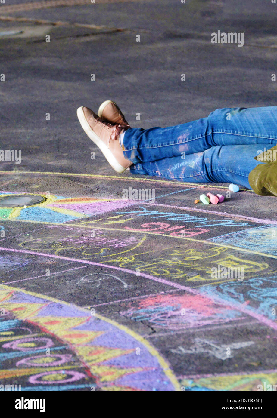 Woman sitting on pavement with chalks for drawing Stock Photo