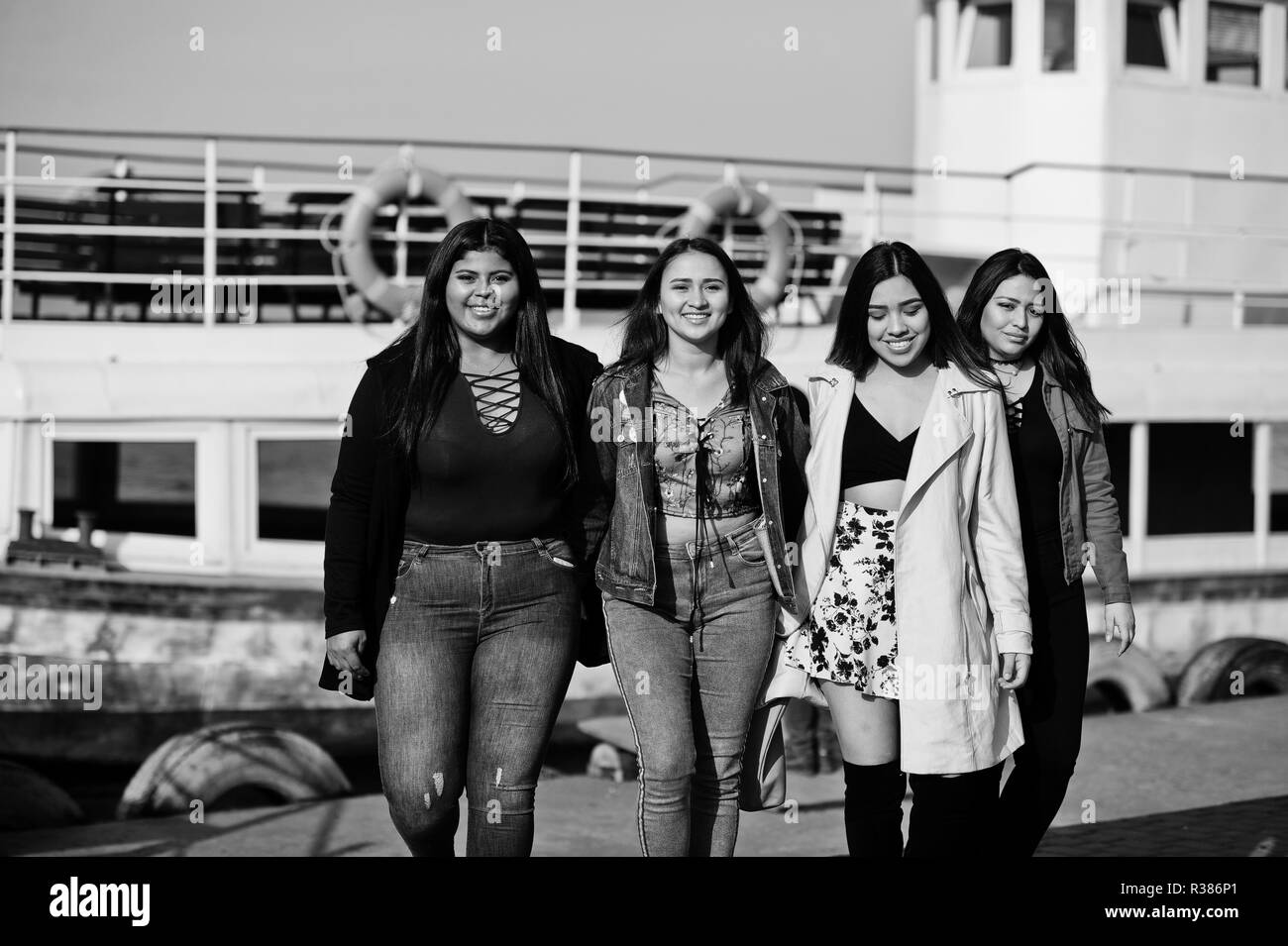 Group of four happy and pretty latino girls from Ecuador posed against boat. Stock Photo