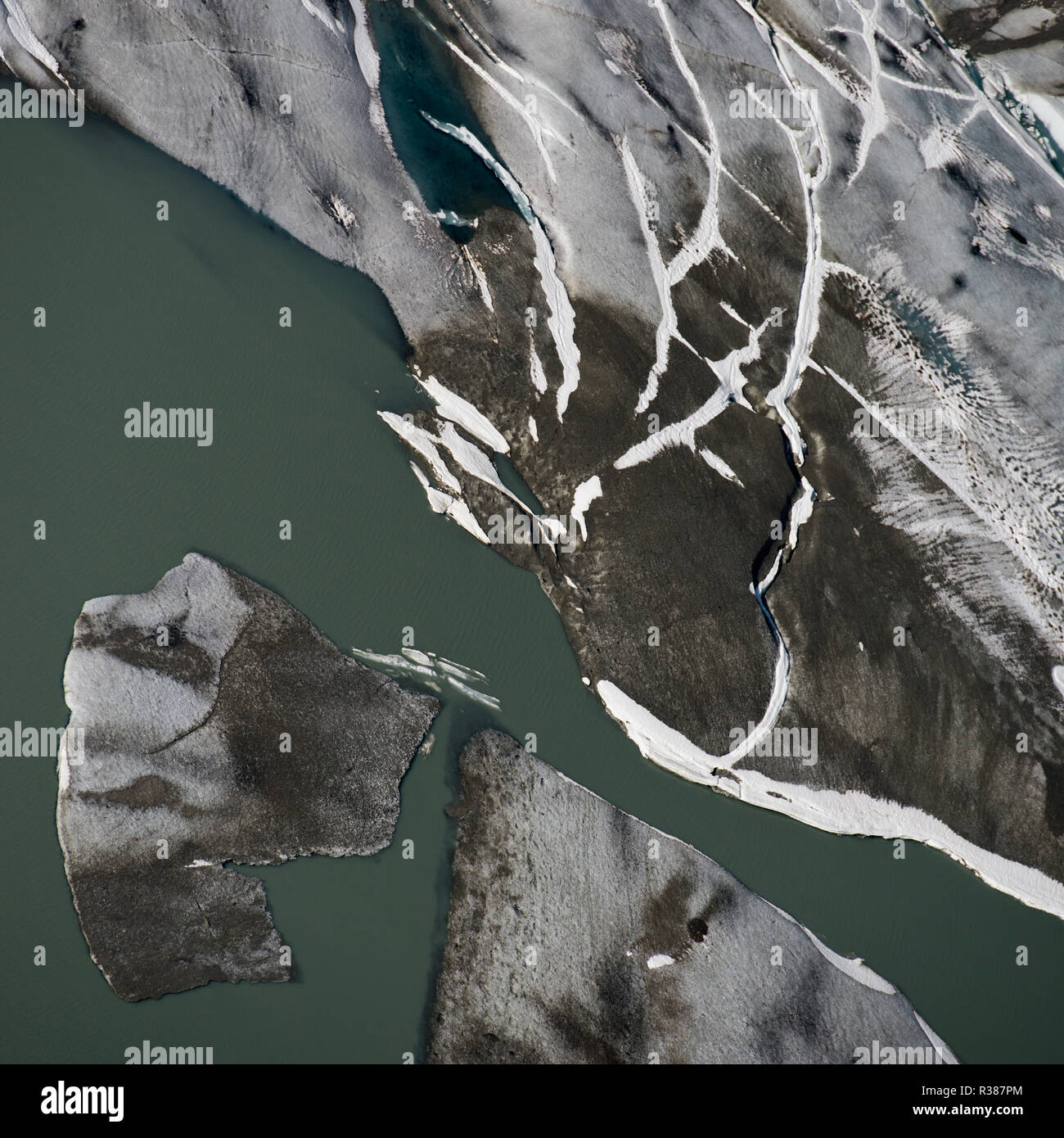 An aerial closeup of the terminus from the Tunsbergdalsbreen indicates a number of debris covered ice bergs in the lake. Tunsbergdalsbreen is a glacie Stock Photo
