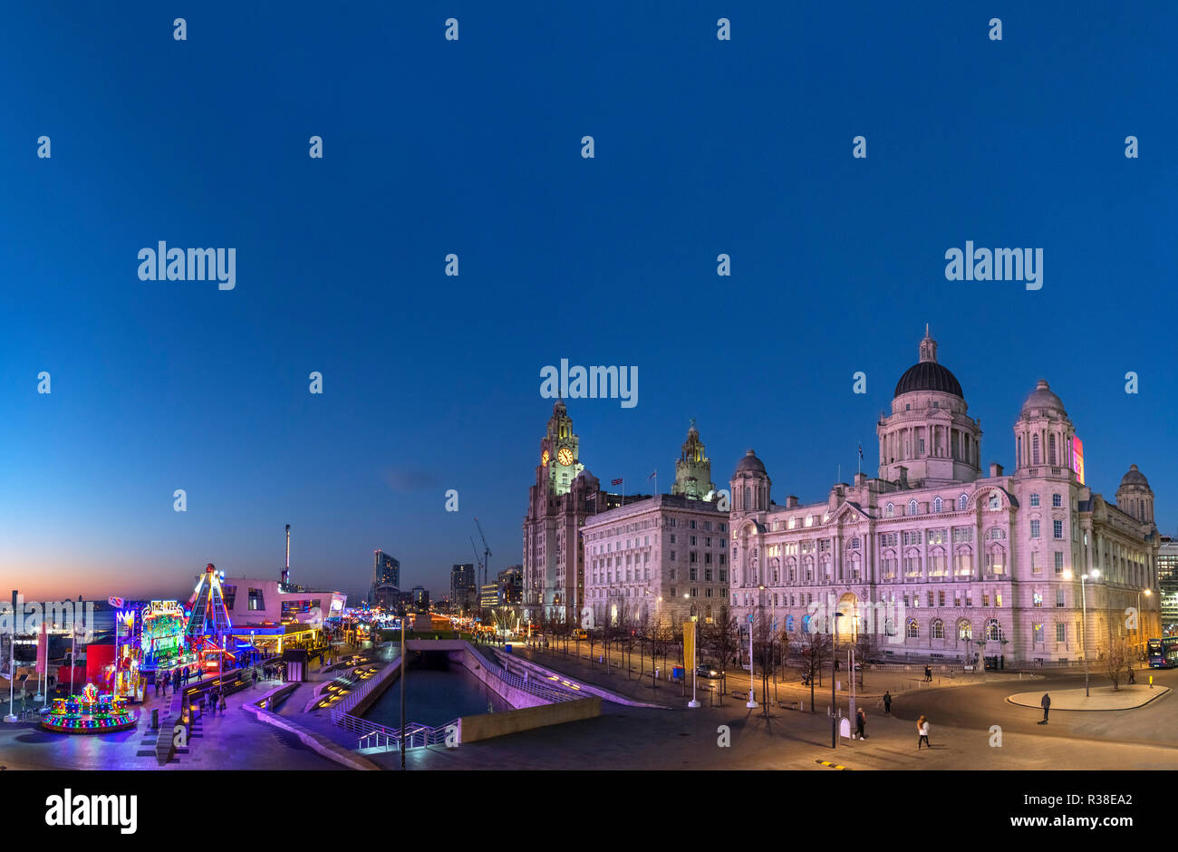 The Christmas Ice Festival fairground and Three Graces at night, Pier Head, Liverpool, England, UK Stock Photo