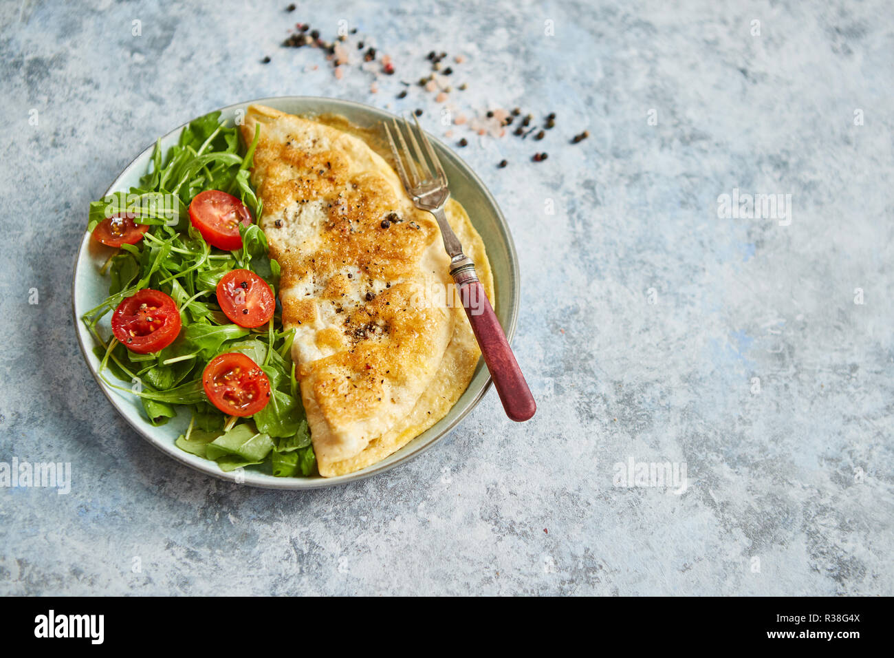 Classic egg omelette served with cherry tomato and arugula salad on side Stock Photo