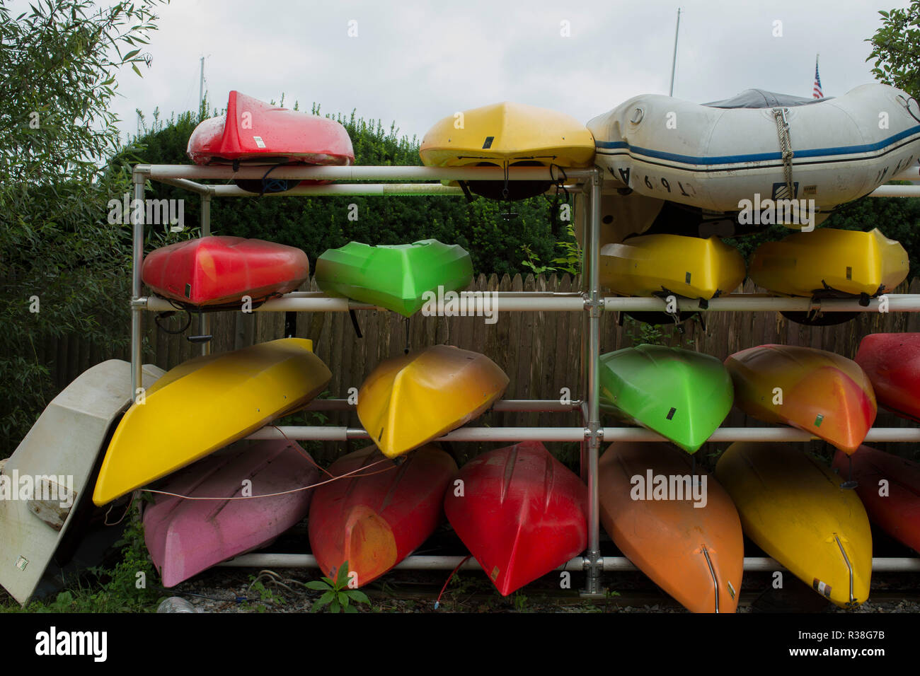 Kayaks on metal rack, wood fence and bushes in background. Essex is a pretty village, white collar executives with beautiful homes. Connecticut River. Stock Photo