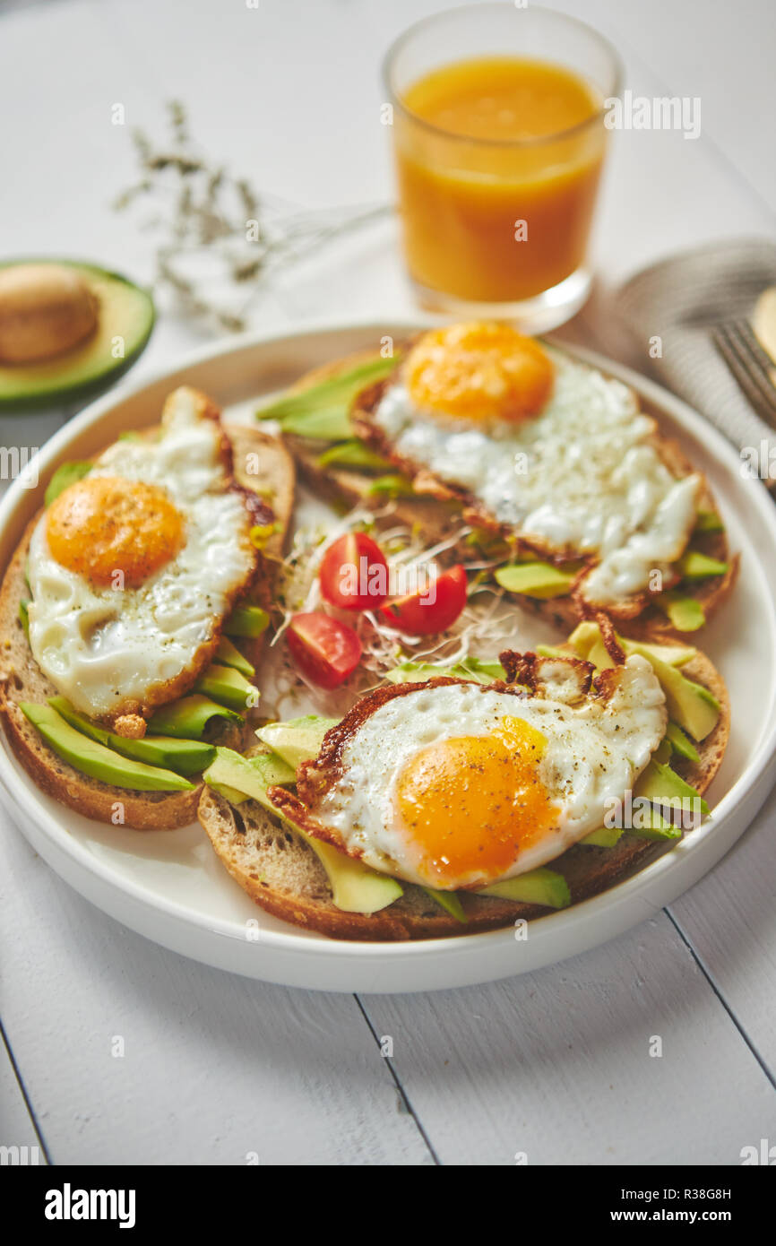 Delicious healthy breakfast with sliced avocado sandwiches with fried egg Stock Photo