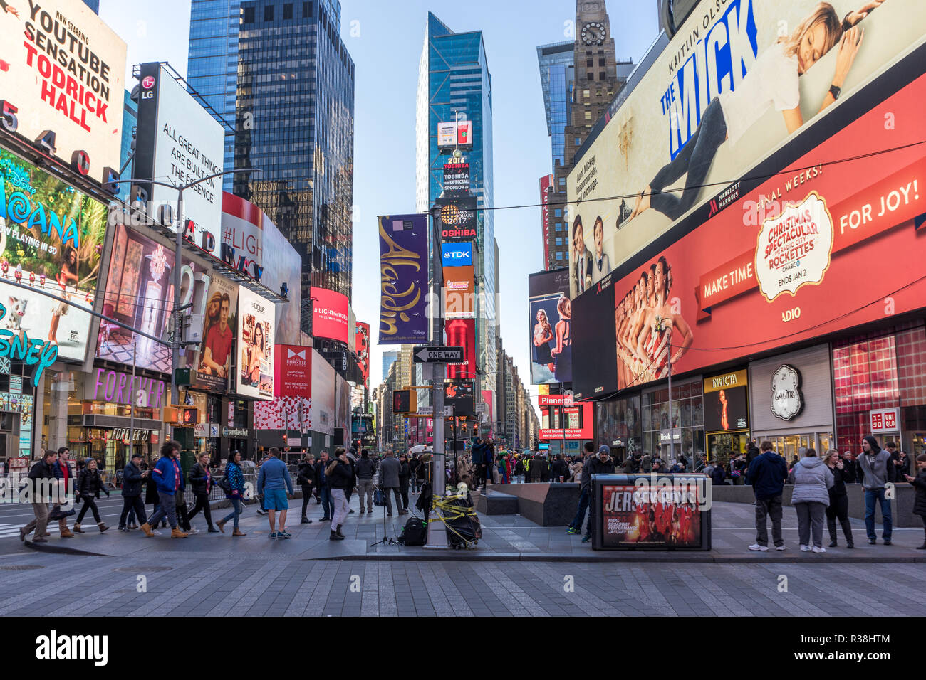 New York City, USA - December 25 2016: View TIme Square with no cars, a crowd of people walking by on the sidewalk, and multiple advertising signs in Stock Photo
