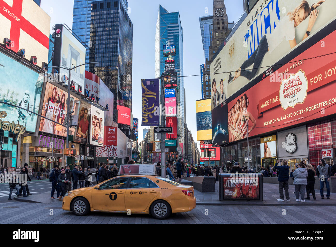 New York City, USA - December 25 2016: View TIme Square a yellow taxi cab driving by, a crowd of people walking by on the sidewalk, and advertising si Stock Photo