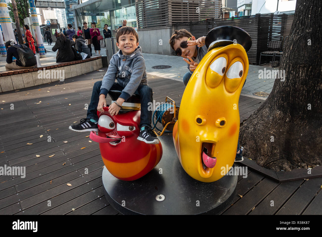 Youung brothers pose for a photo sat on models of two cartoon characters  from the Korean cartoon 'Larva' Stock Photo - Alamy