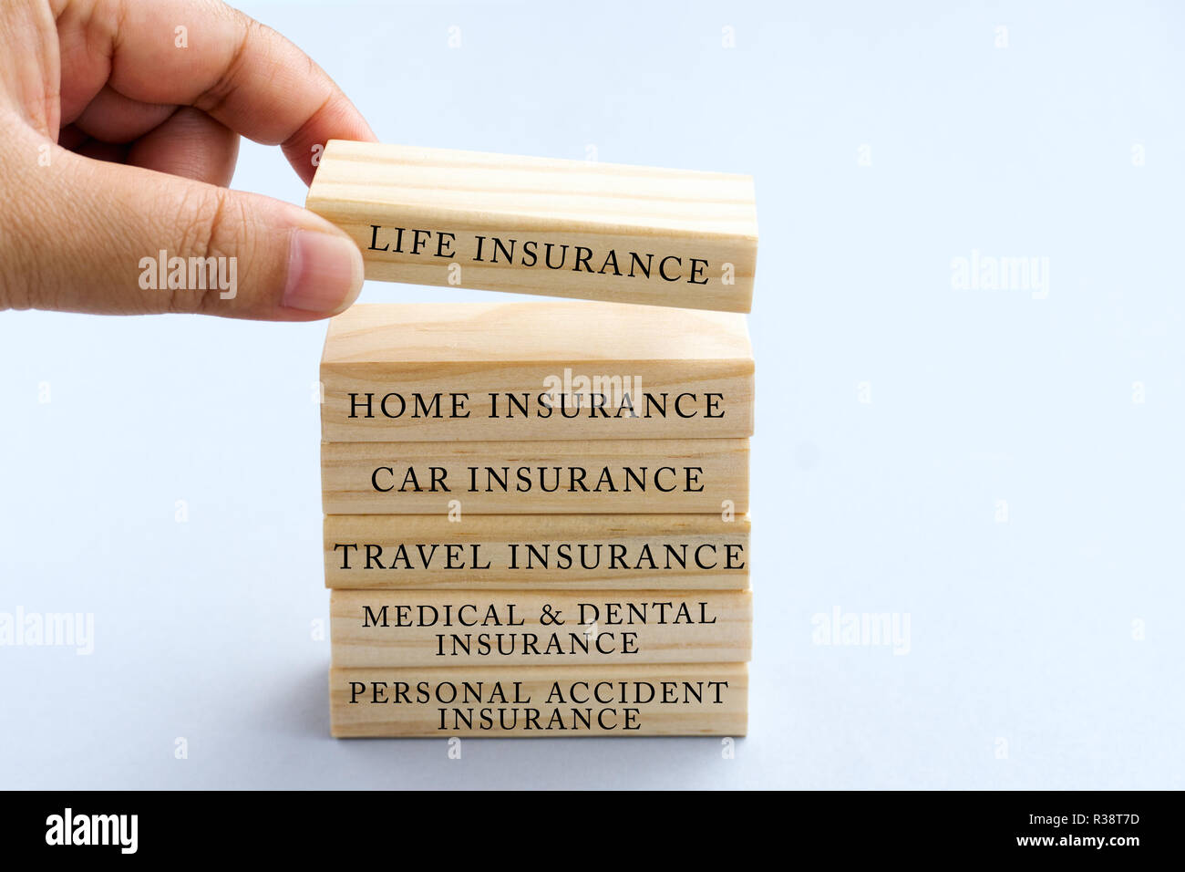 Hand Picking Wood Block with Word Life Insurance. Business Concept Type of Insurances on Wood Top Block with Word: Life, Home, Car, Travel, Medical an Stock Photo