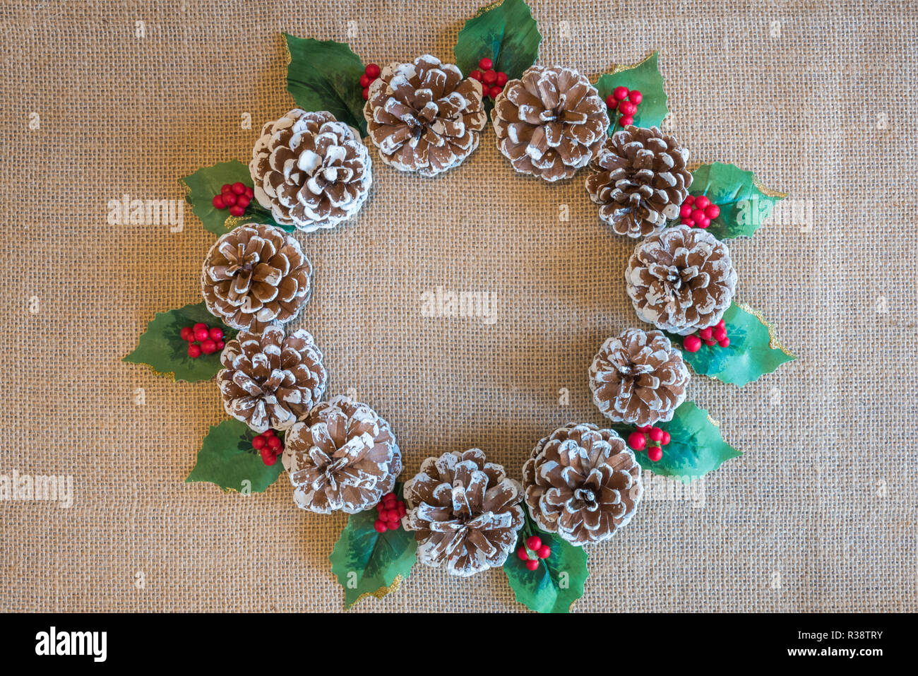 Christmas wreath of pine cones, holly leaves, and red berries on rustic ...