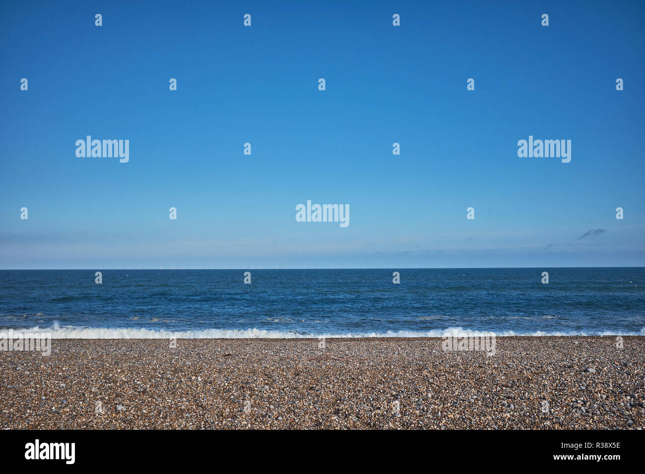 Pebble beach with no people at Clay On Sea with large amount of blue sky and small amount of sea Stock Photo