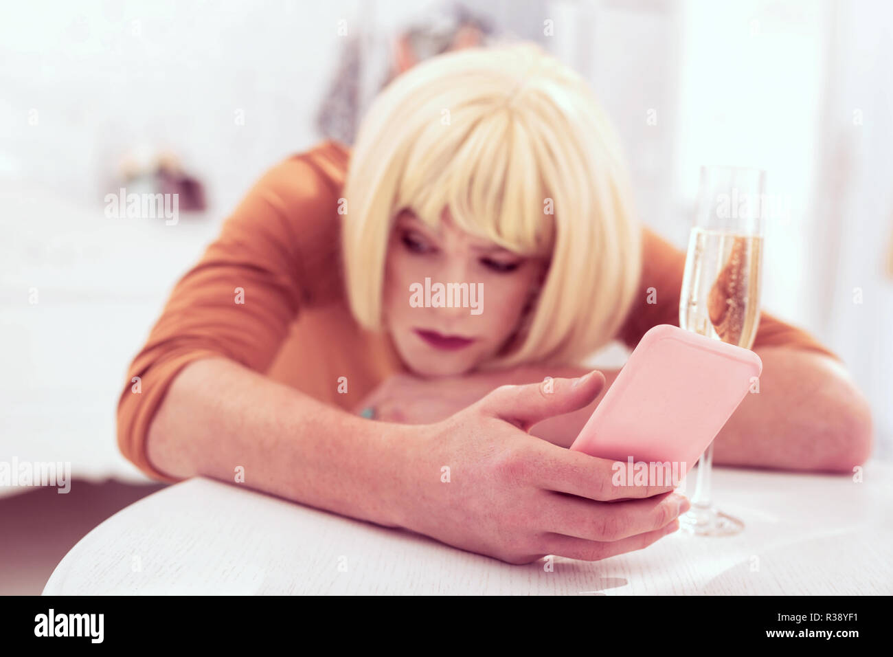 Interesting transgender with blond wig carrying pink mobile phone Stock Photo