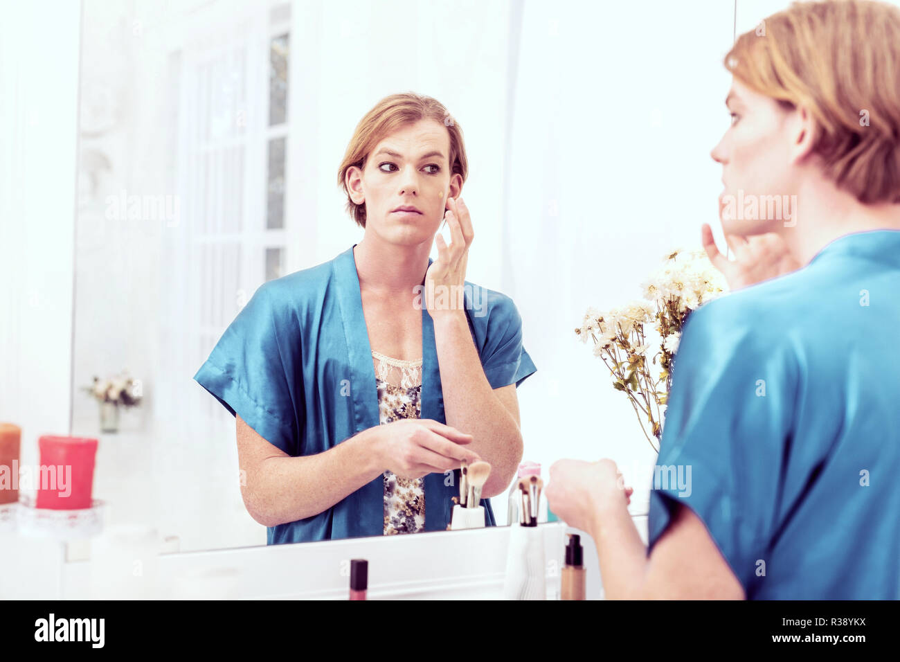 Calm short-haired young gender-queer applying full coverage foundation Stock Photo