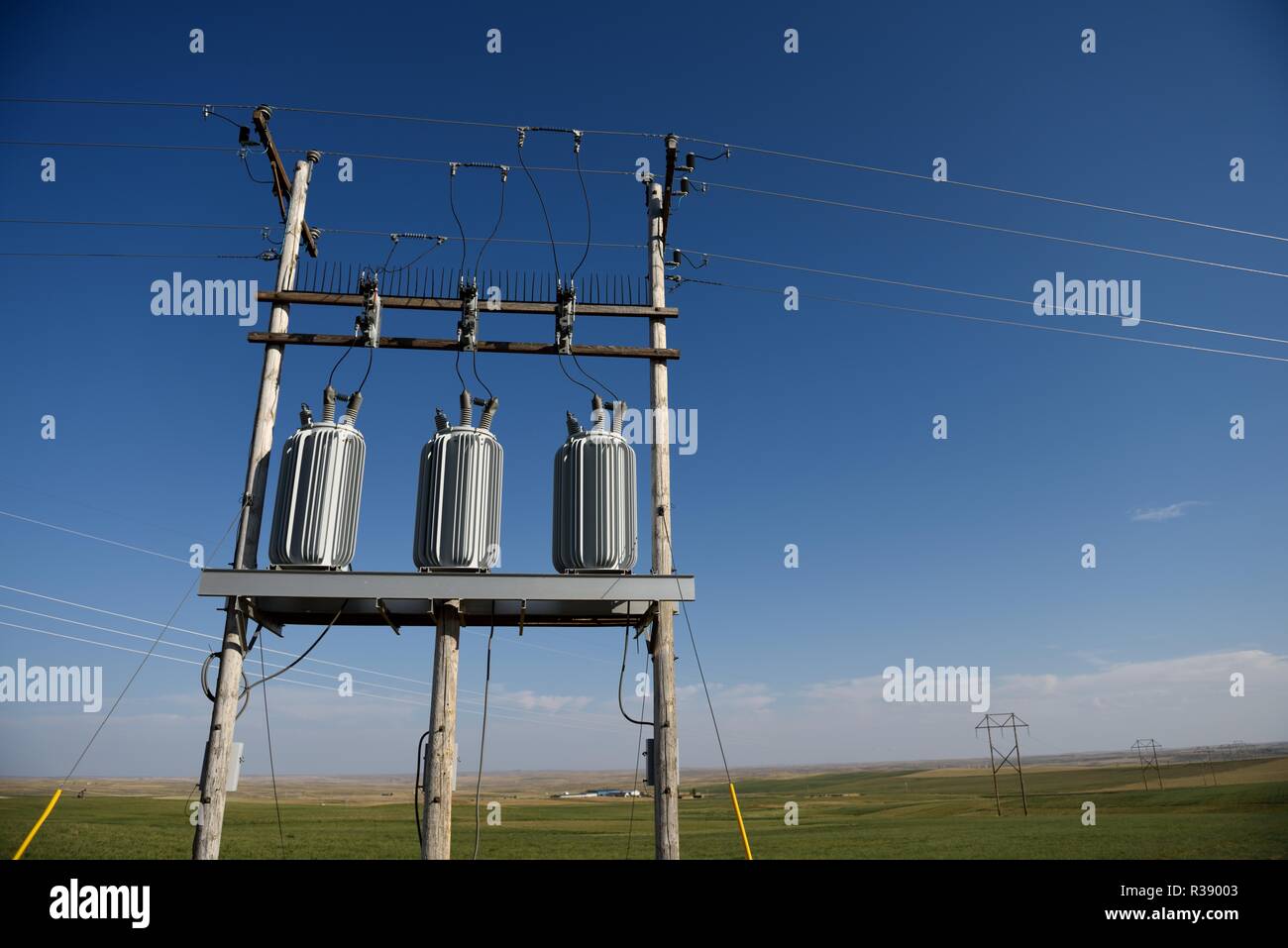 Electrical grid infrastructure, transformers, overhead high voltage power lines, against a blue sky in Wyoming, USA. Stock Photo