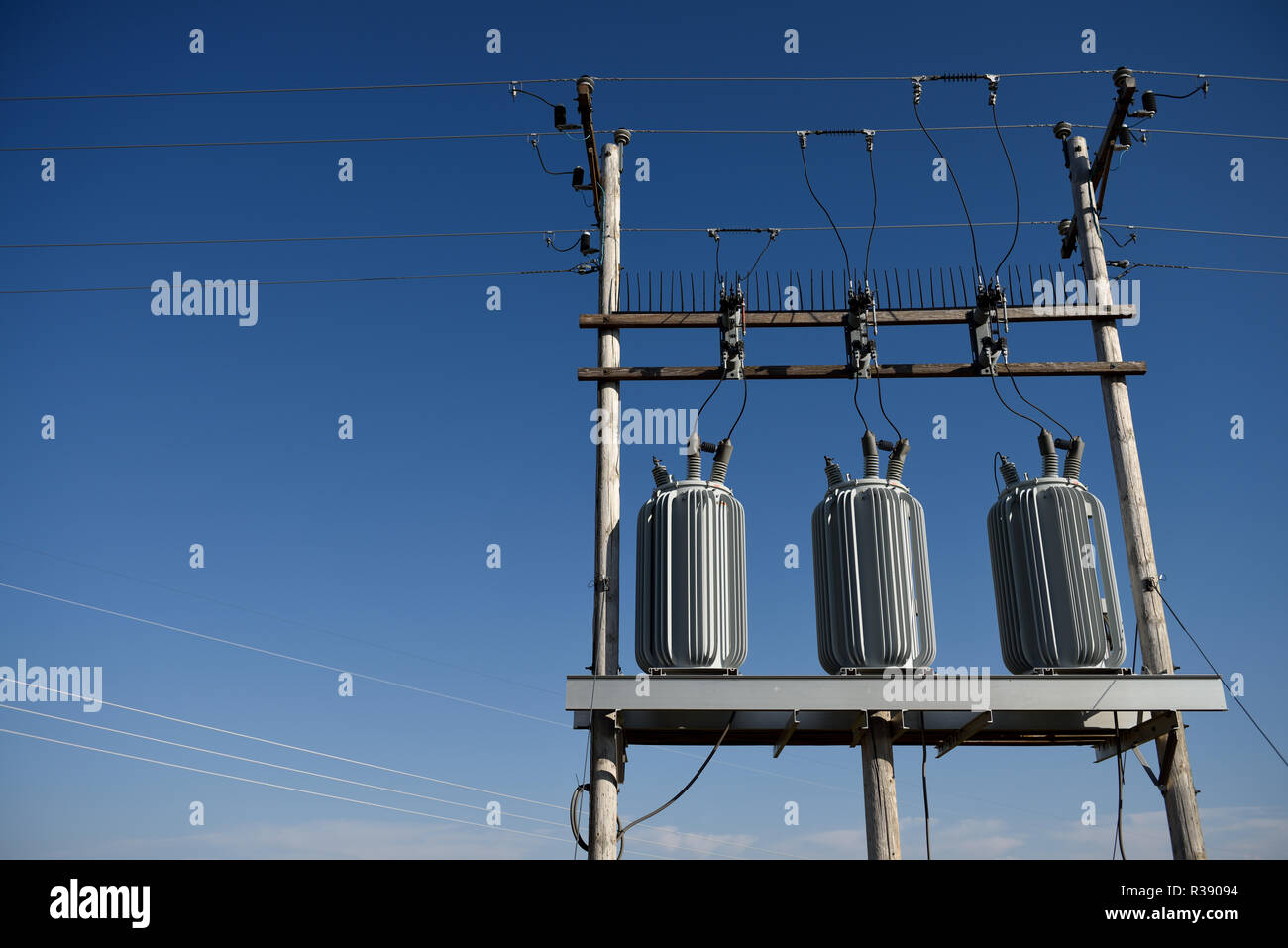 Electrical grid infrastructure, transformers, overhead high voltage power lines, against a blue sky in Wyoming / USA. Stock Photo