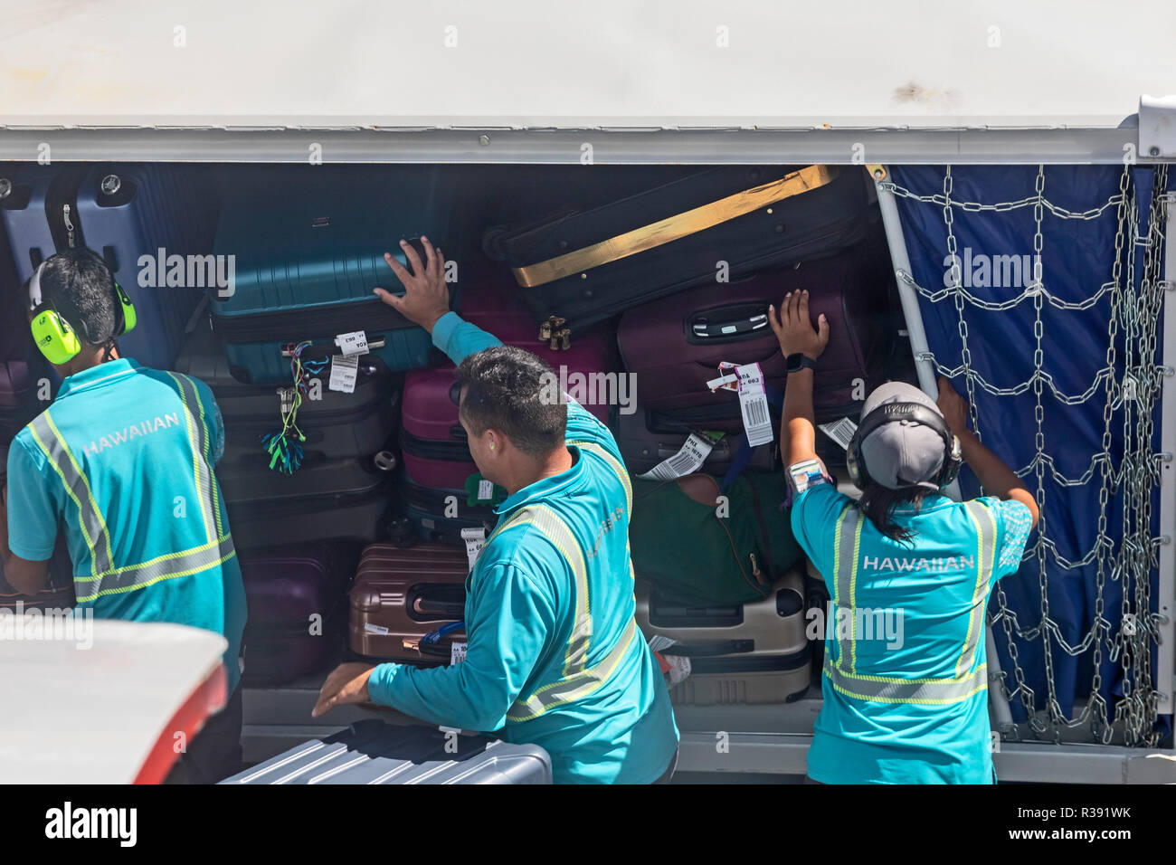 Kailua-Kona, Hawaii - A Hawaiian Airlines ground crew unloads luggage from an American Airlines jet at Kona International Airport on Hawaii's Big Isla Stock Photo