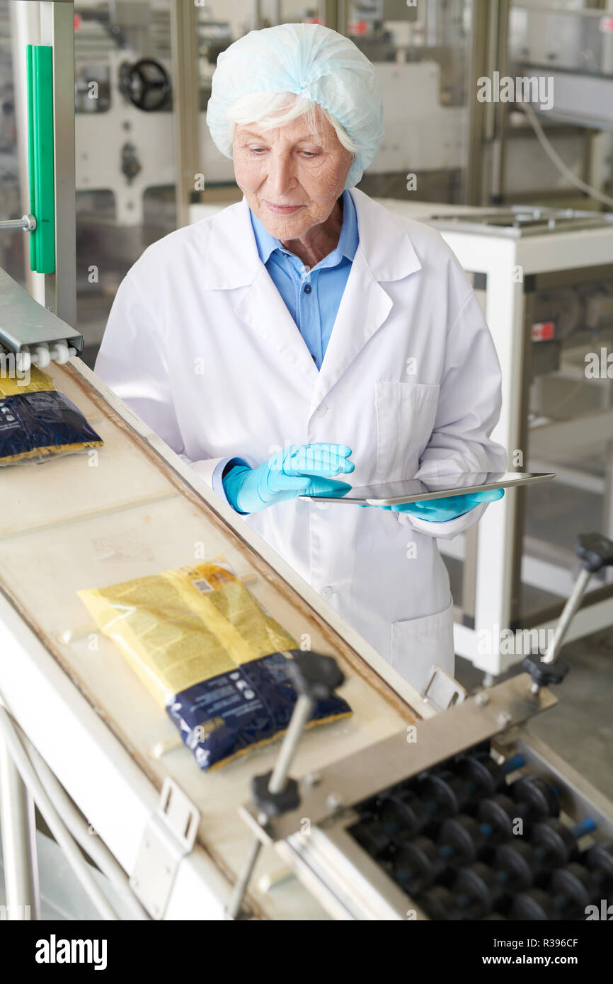 Smiling Senior Woman at Packaging Line Stock Photo