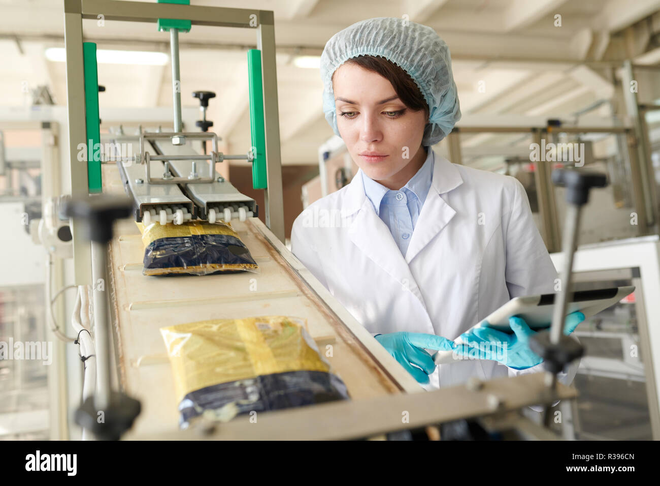 Young  Woman Controlling Packaging Line Stock Photo