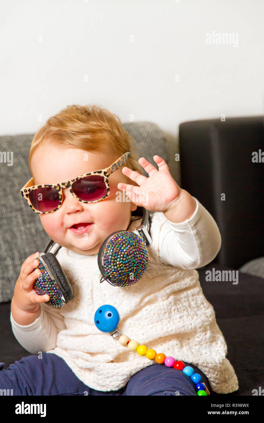 funny baby girl with headphones and sunglasses Stock Photo