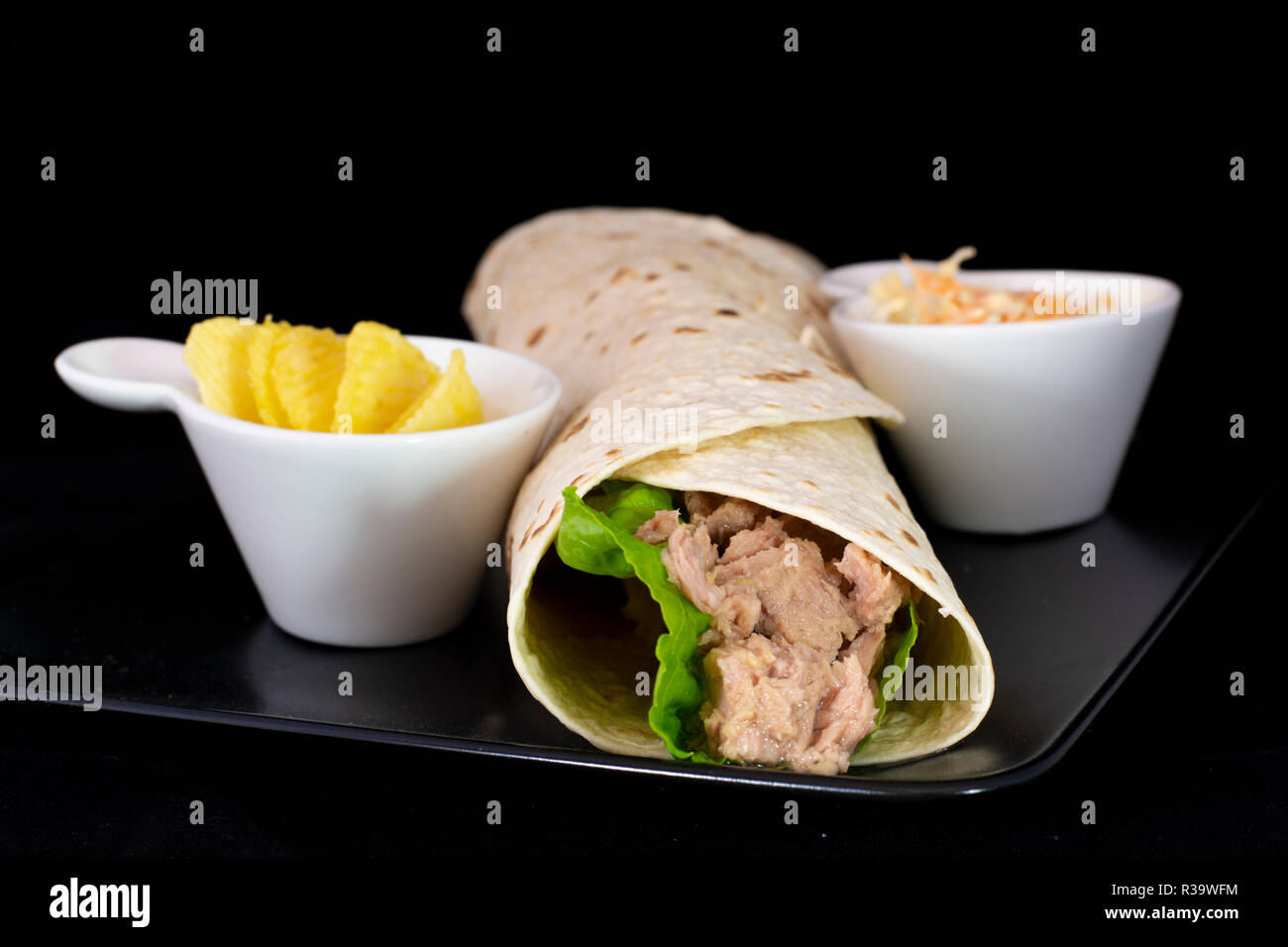Delicious tuna fish wrap with salad inside with isolated black background Stock Photo
