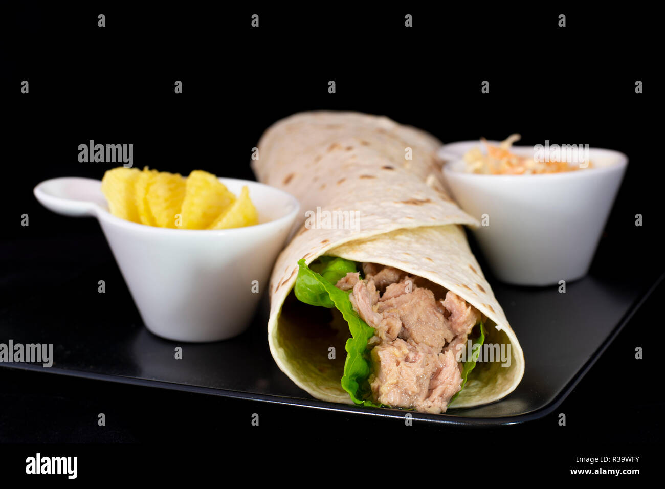 Delicious tuna fish wrap with salad inside with isolated black background Stock Photo