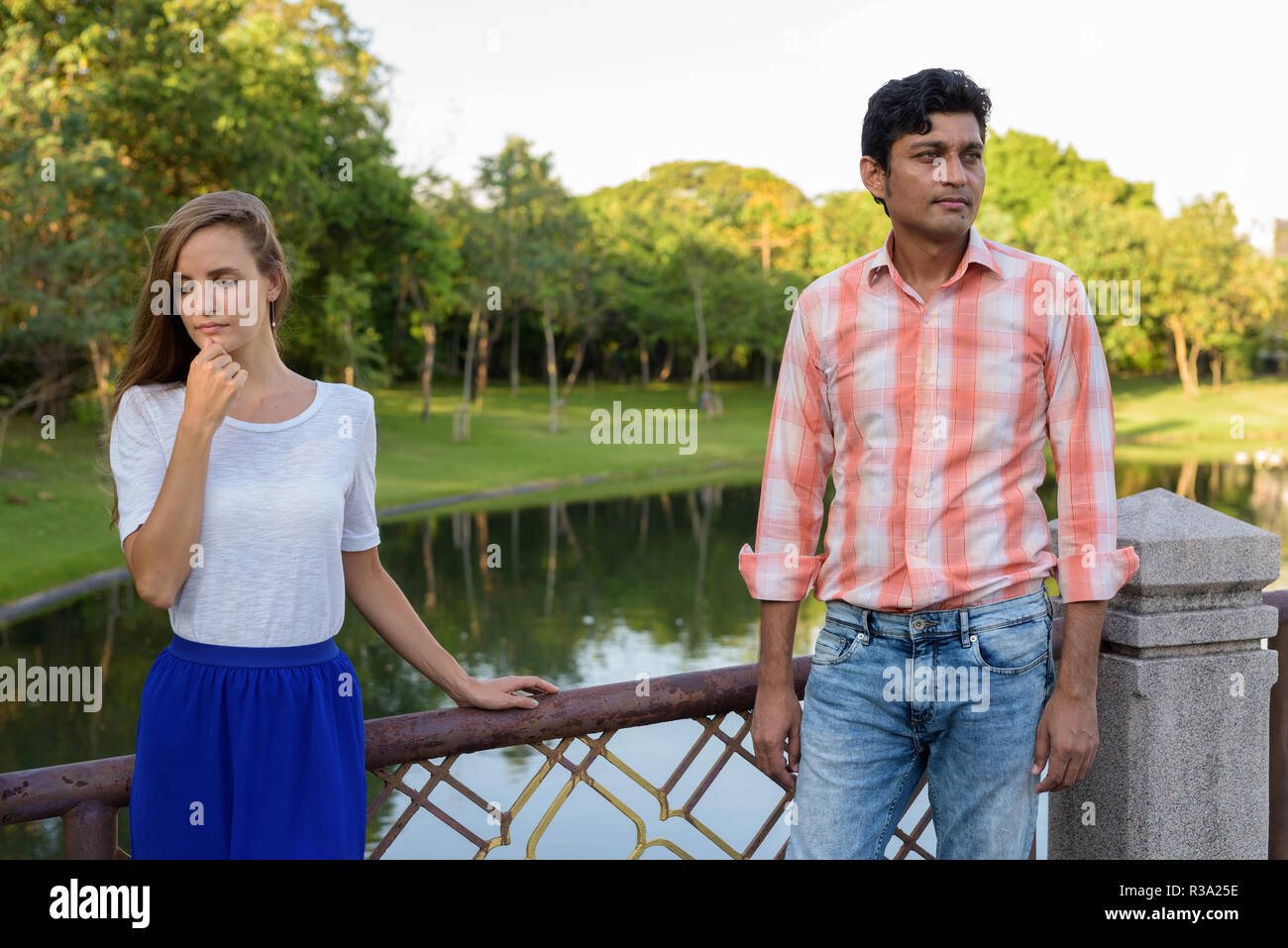 Multi ethnic couple thinking while looking sad on the bridge of  Stock Photo