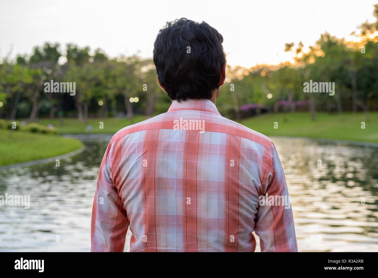 Indian man looking at scenic view of the lake in peaceful green  Stock Photo