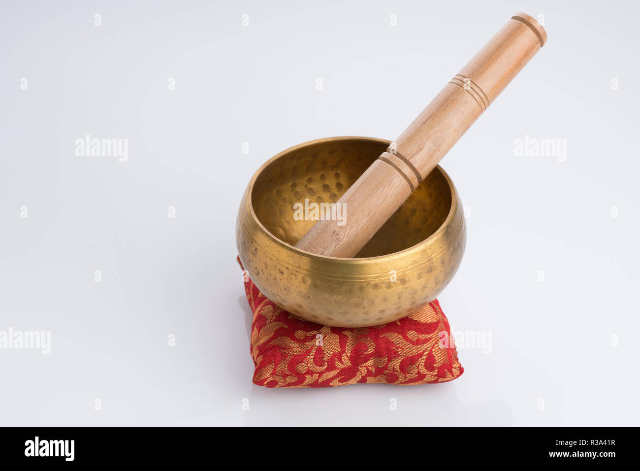 Tibetan Singing Bowl on Red Cushion Isolated on White Background Stock Photo