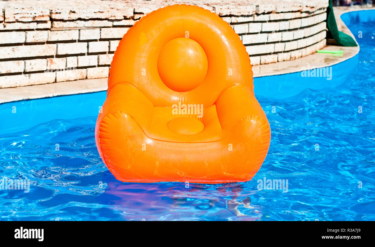 Orange Inflatable armchair in the pool summer time Stock Photo