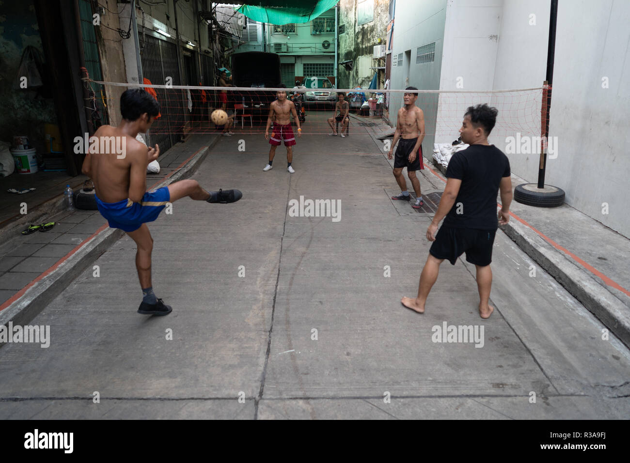 Men seen playing Sepak takraw or foot volleyball in Chinatown, Bangkok, Thailand. Daily life in Bangkok capital of Thailand. Stock Photo