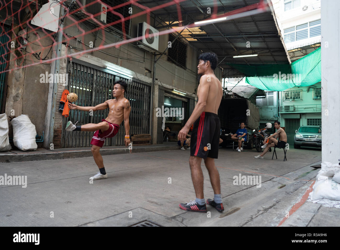Men seen playing Sepak takraw or foot volleyball in Chinatown, Bangkok, Thailand. Daily life in Bangkok capital of Thailand. Stock Photo