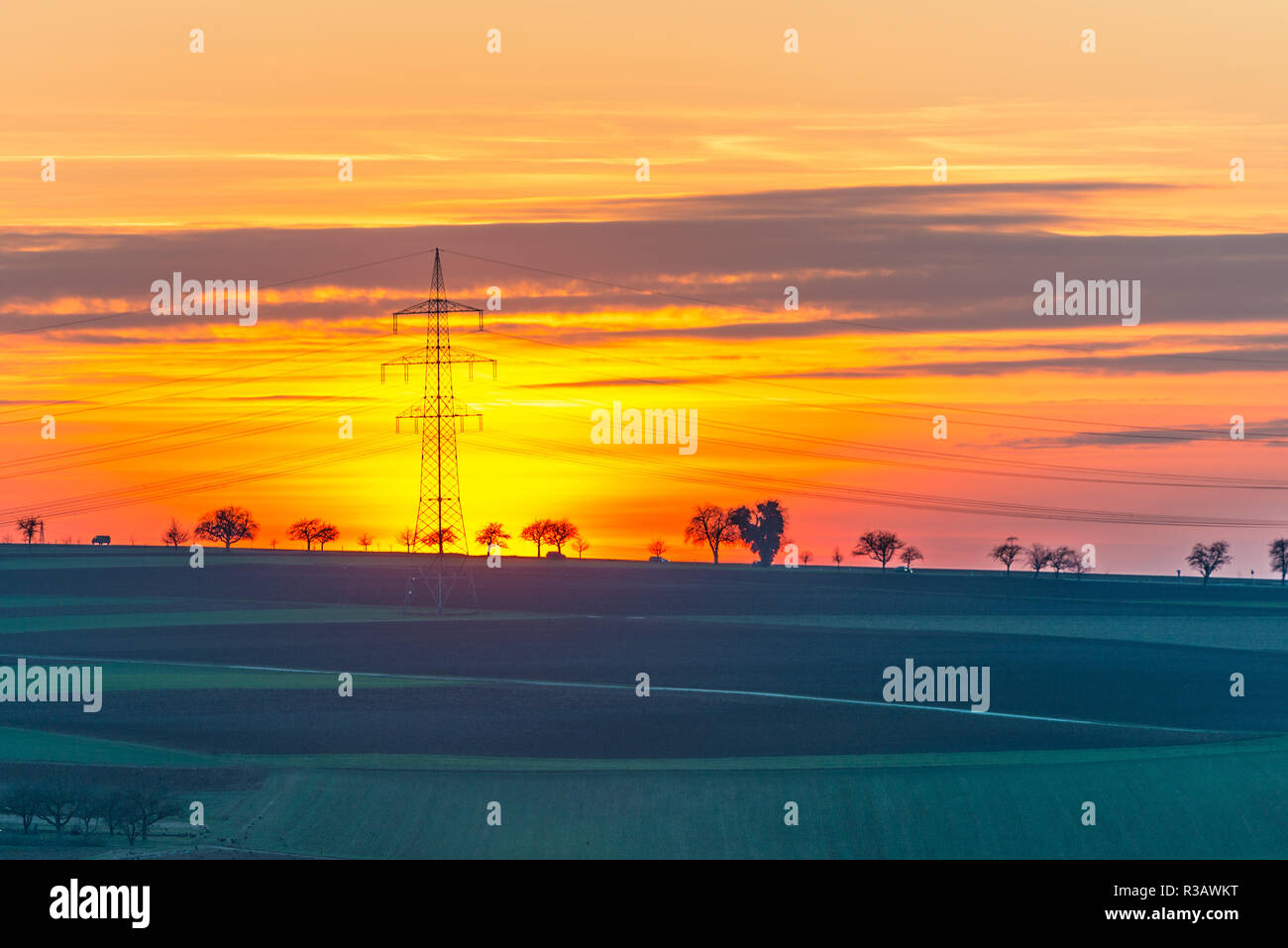 sun setting behind electricity pylon Stock Photo