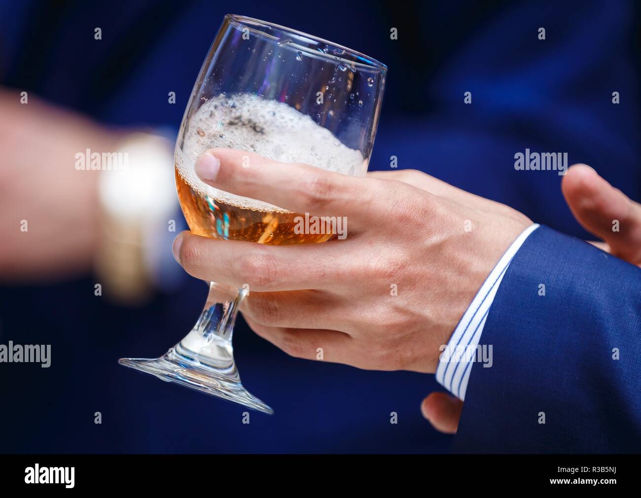 a hand of a man holding a glass of champagne or wine. Stock Photo