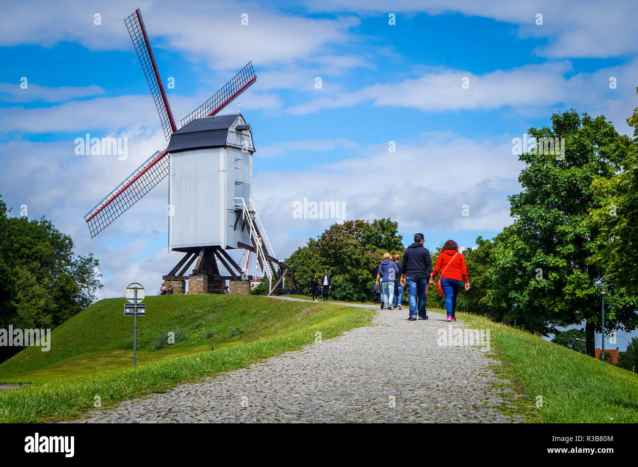 White traditional windmill with people on a beautiful bright day at the historical Bruges town. Stock Photo