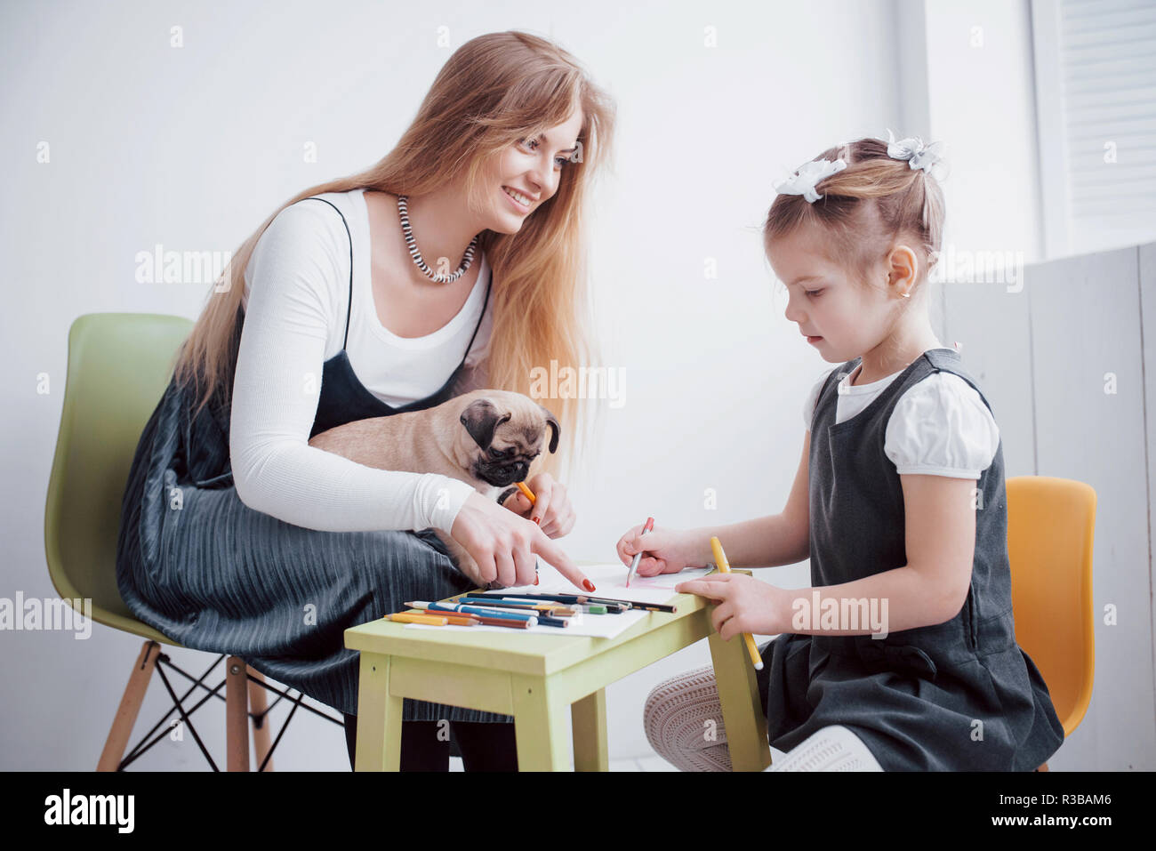 mother and child daughter draws are engaged in creativity in kindergarten. small pug with them Stock Photo